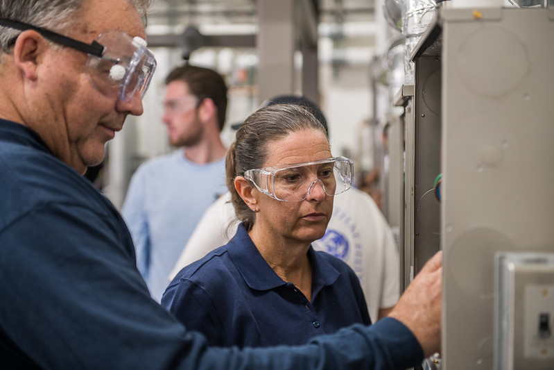 Two people wearing safety glasses examen equipment.