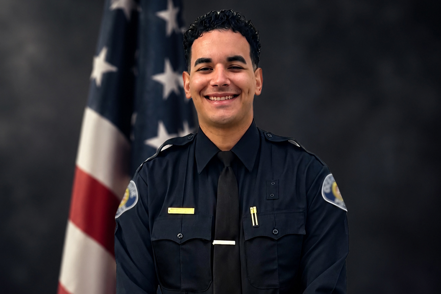 A police academy graduate smiling at the camera.
