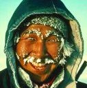 photo of an Inuit man in the winter--he is wearing a traditional parka; his eye brows and mustache are caked with ice