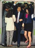 photo of urban Japanese businessmen and women getting on and off of a crowded commuter train