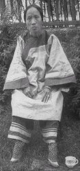 Black and white photo of an early 20th century Chinese woman with feet that been bound when she was a child