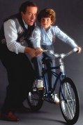 photo of a North American father showing his son how to ride a bicycle