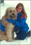 photo of a woman in the snow hugging her big dog