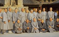 photo of 18 Asian Buddhist monks all wearing the same kind of gray robes.
