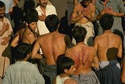 photo of a crowd of Shiite Muslim men in Iran beating their own chests and backs