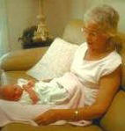 photo of a woman looking at her newborn grandchild in her lap