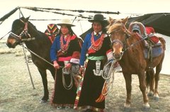 Photo of two Mongols standing next to their horses