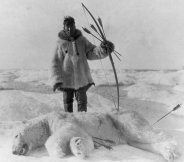 Early 20th century photo of an Eskimo polar bear hunter with a bow and arrows