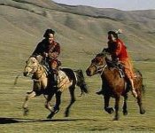 Photo of two Mongol men riding their horses