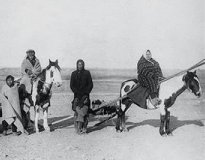 Photo of a North American Plains Indian family traveling by horse with a travois (sled)