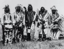 Photo of five North American Plains Indian men in ceremonial clothing