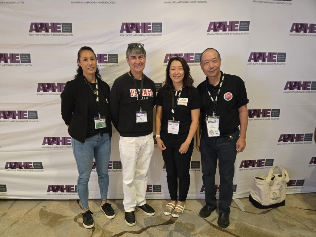 4 APAHE members standing posing for a picture in front of the APAHE Conference 2026 backdrop