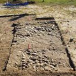 A broken cobble stone floor exposed in an excavation unit