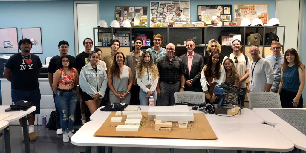 A group of the Architecture students and their istructors posing behind an architectural model.