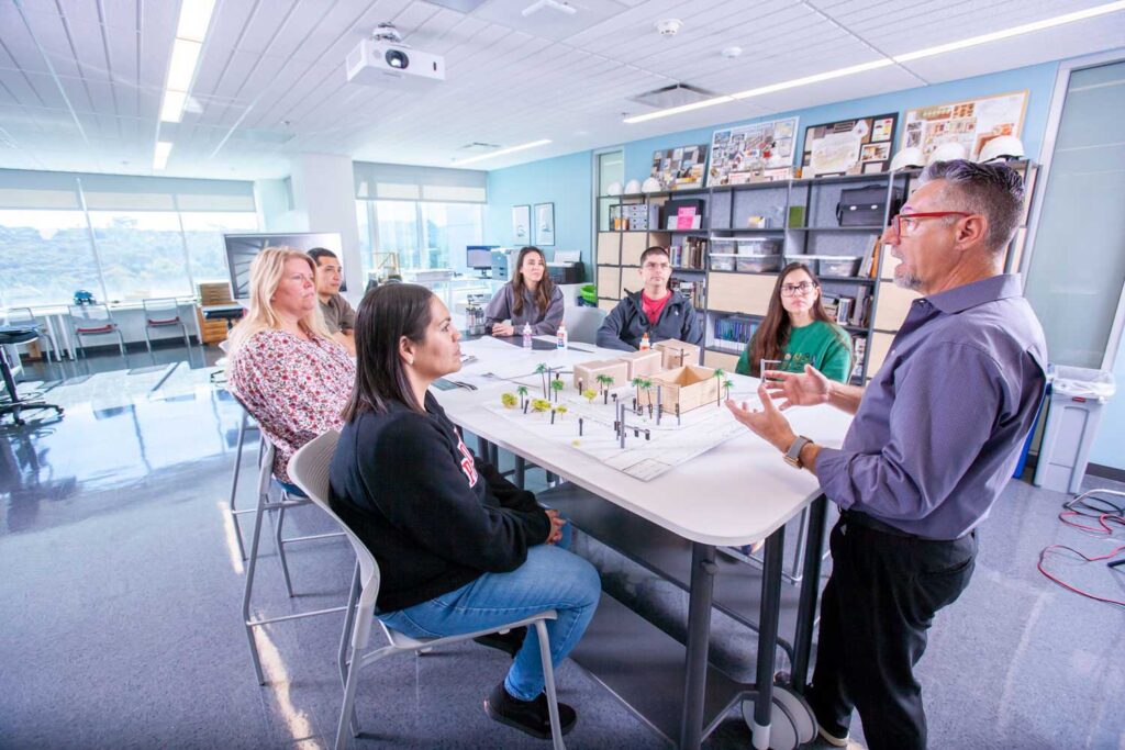 Several students and a professor gathered in a building modeling setting.