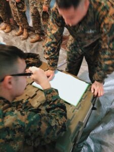 Military personel in uniform review homework with focus on detail.
