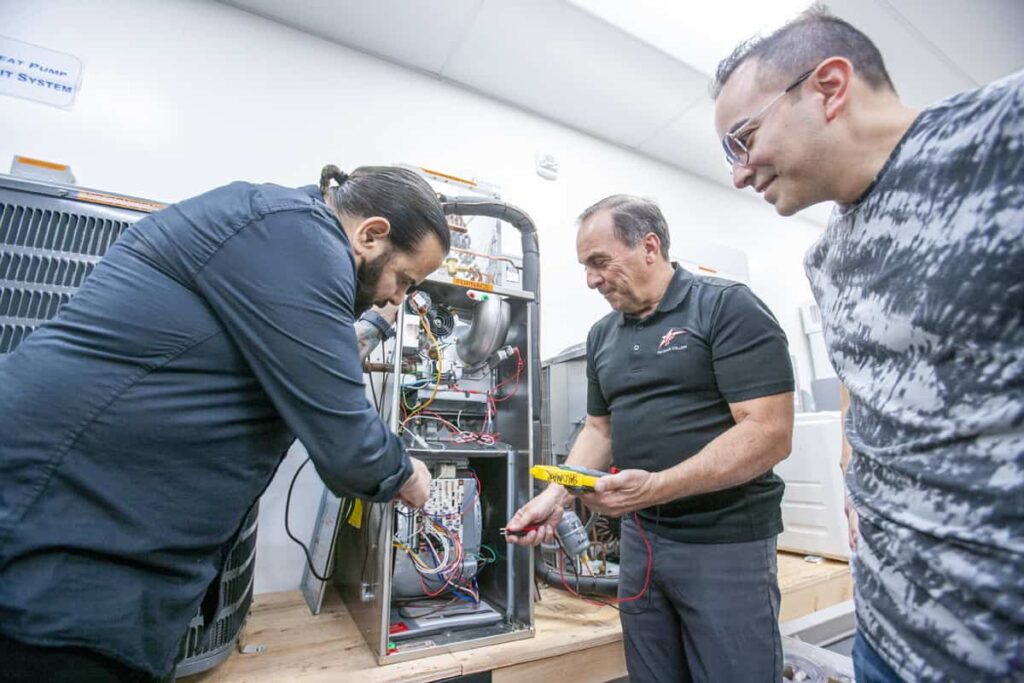 HVAC instructor guides students as they troubleshoot heating and cooling equipment during a hands-on lab.