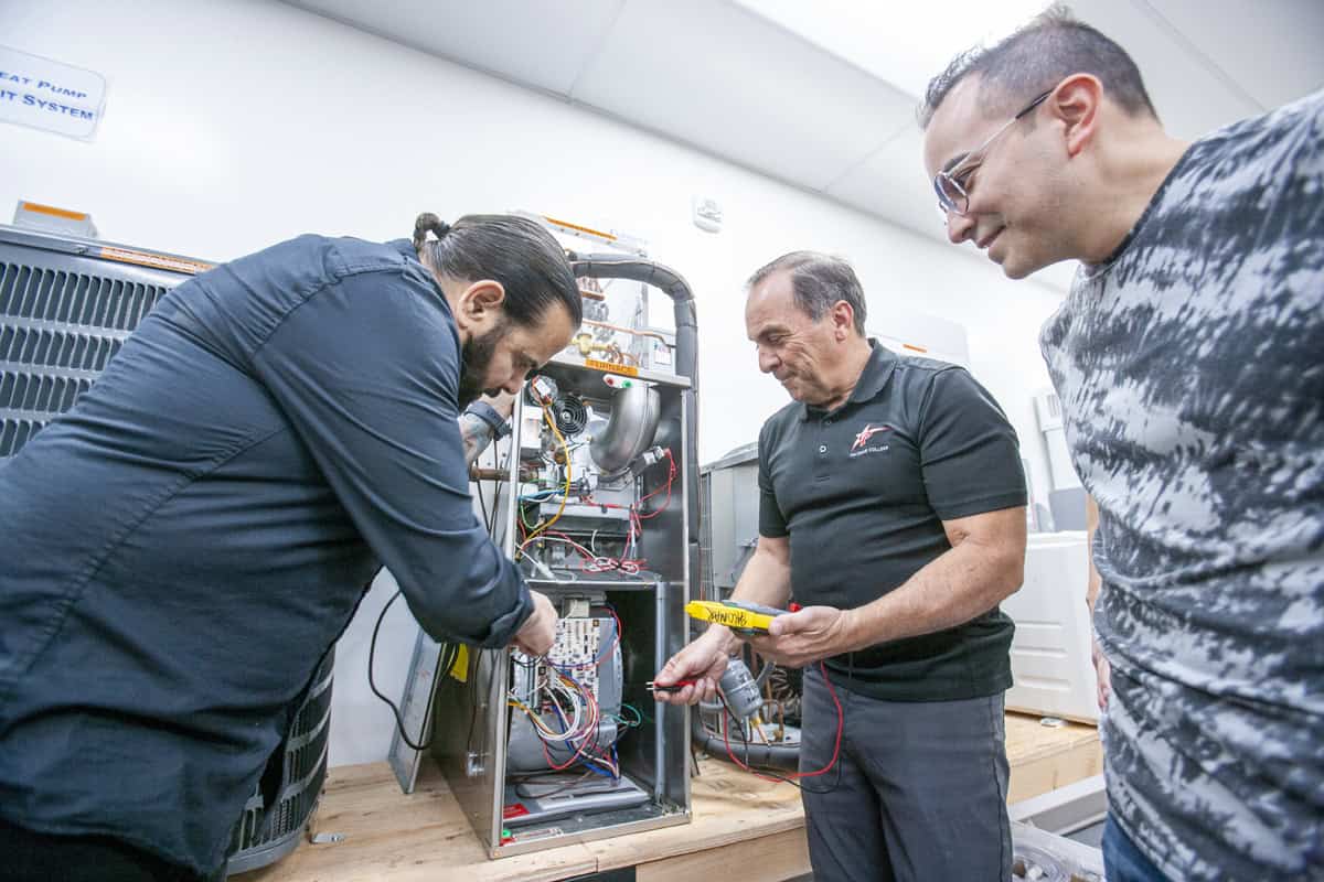 HVAC instructor guides students as they troubleshoot heating and cooling equipment during a hands-on lab.