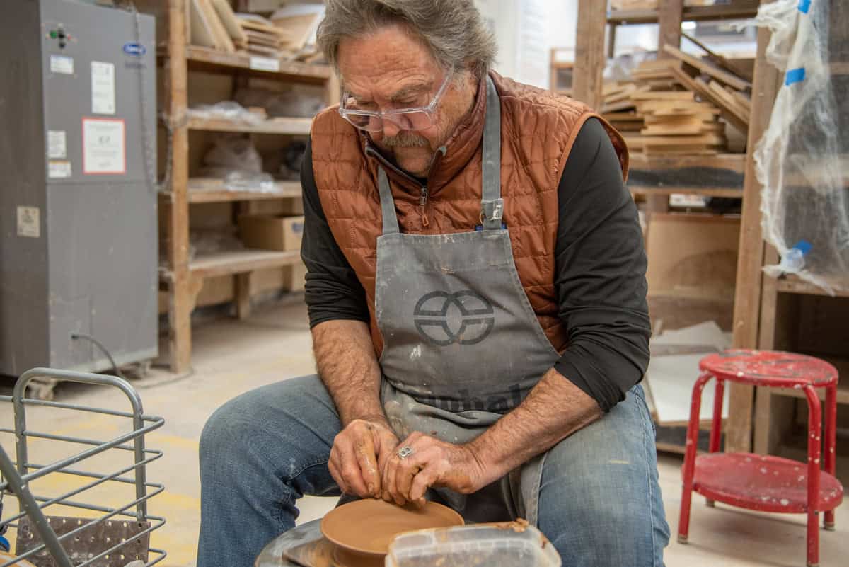 Ceramics student shapes clay on a pottery wheel during a hands-on class.