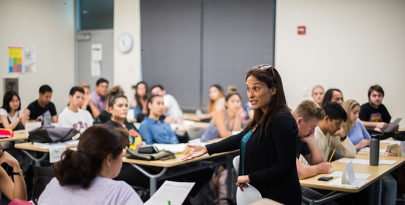 Students in desks listening to a professor lead a lecture