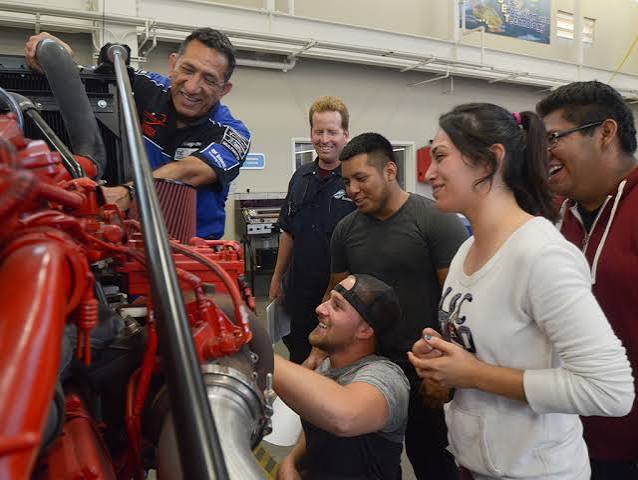 Students and instructor look at a diesel engine.