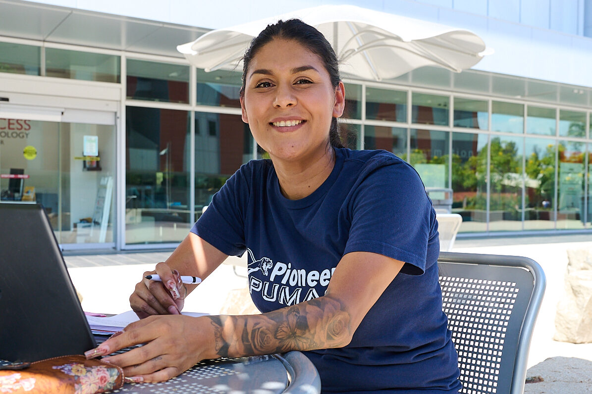 Woman with her laptop sitting outside at a table at Palomar College.