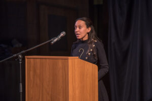 Haben Girma stands at a light-wood colored podium with a microphone near her face.