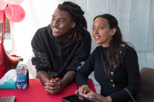 Haben Girma smiles next to a student, a black man with long hair and a black swearshirt.