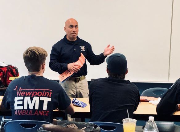 EMT Instructor at the front of a classroom engaged in a lecture