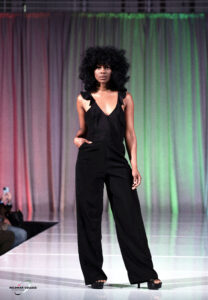 Model wearing a black jumpsuit on the runway.