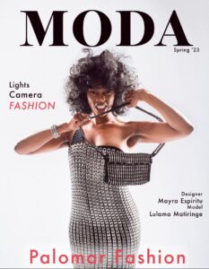 The cover of the MODA fashion magazine with a black model with big hair on the cover wearing a silver dress made of pop top tabs.