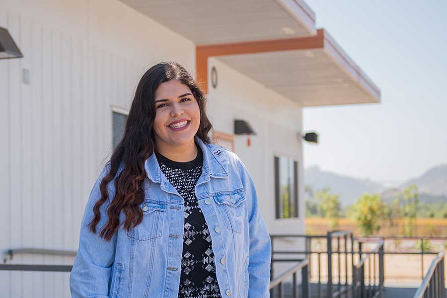Student standing at the Fallbrook Center, smiling
