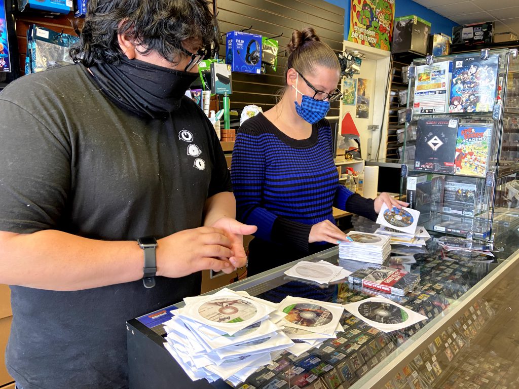 Eric Velasco (l) and a store employee sorts game CDs at Calico Games. (Lucas Vore/IMPACT Magazine)