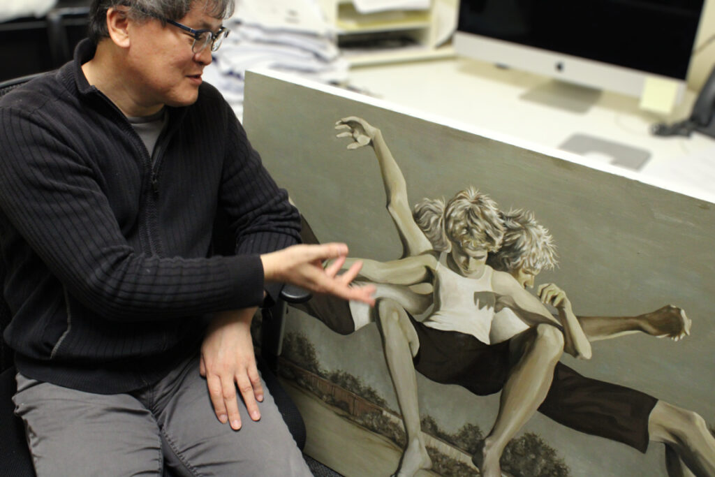 Professor Bo Kim sits gestures to one of his students art work. 