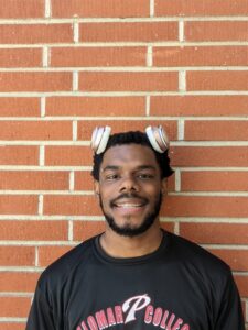 Isaiah Davis stands against a brick wall with a pair of headphones on top of his head.