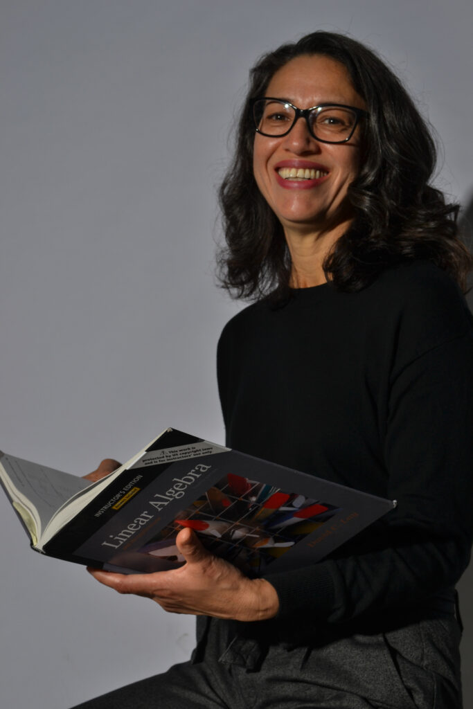 Professor Martha Martinez holds a linear algebra textbook.