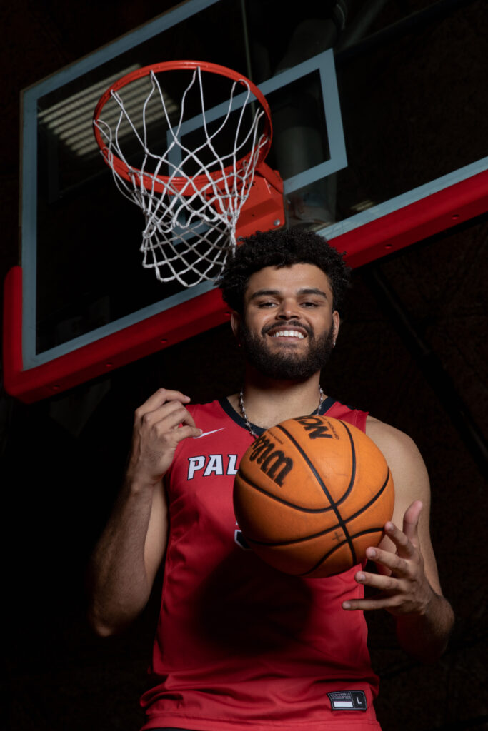 Palomar basketball player Kryztian Walton holds a basketball while standing under a hoop.