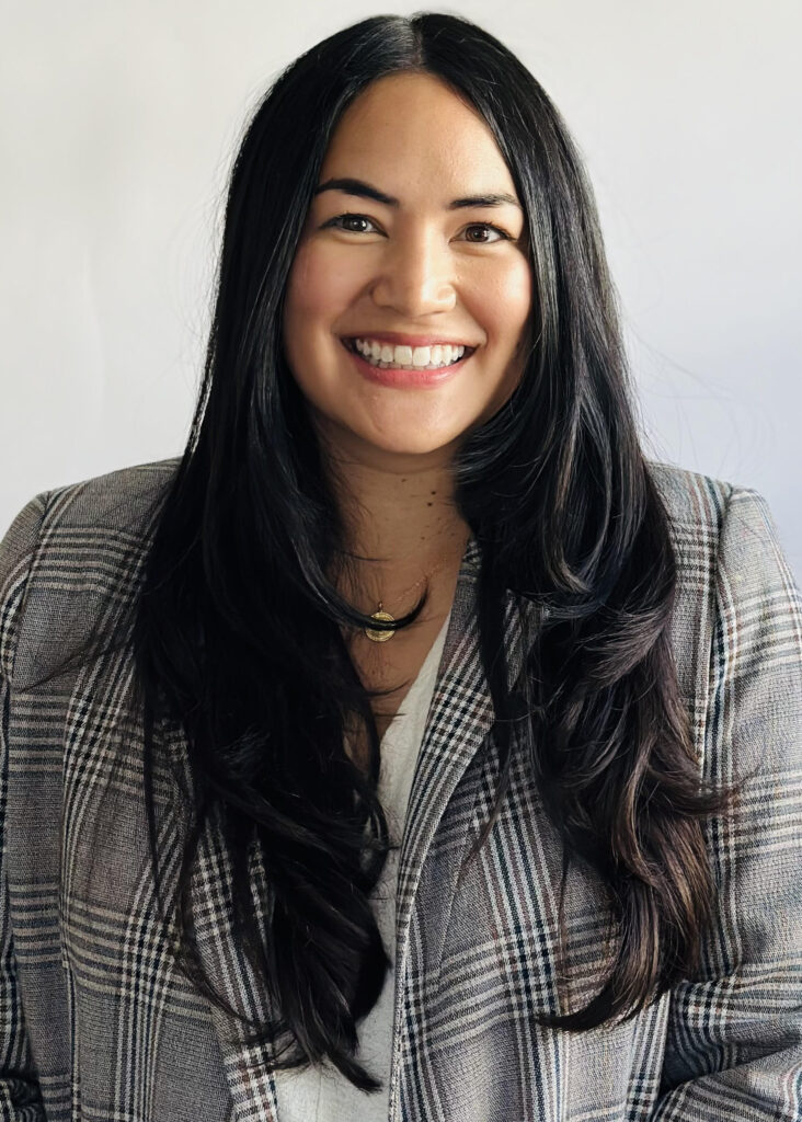 I portrait of a smiling woman with long dark hair dressed in gray blazer.