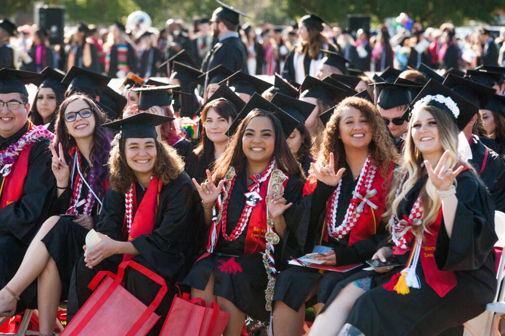 A number of graduates seated and smiling at Commencement