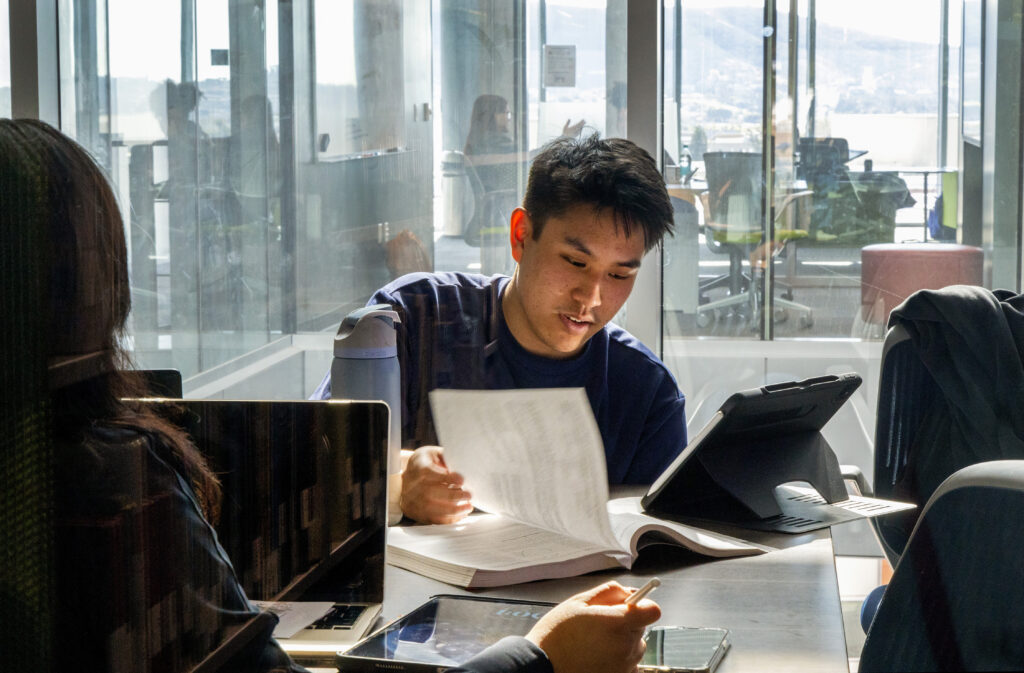 Student studying in the library, flipping through textbook pages