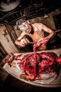 A monster butcher removes entrails from a dead corpse 