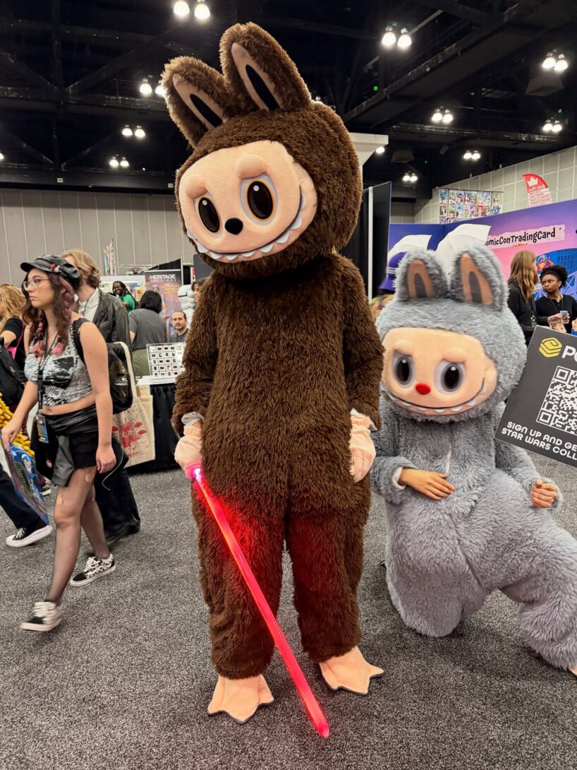 Two Labubus and one is holding a light sabre