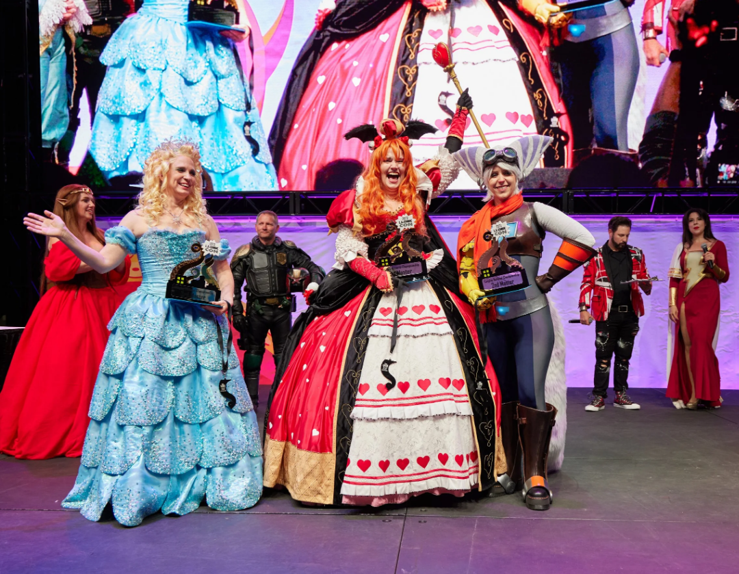Contestants at a cosplay contest. Left to right: Elsa the Ice Queen, The Queen of Hearts, and a steampunk bat