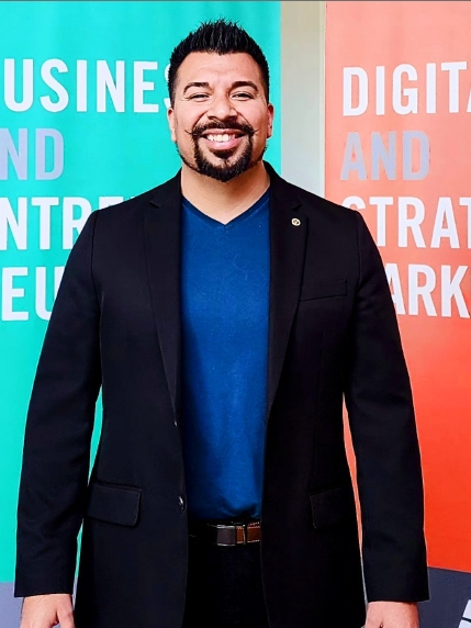 Headshot of Eddie Baltazar standing against a Digital Media backdrop.