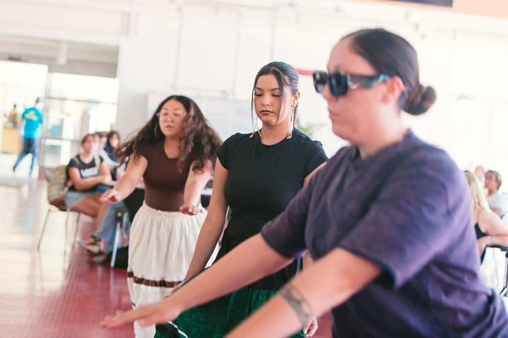 Bird dancers performing inside the Student Union with attendees watching.