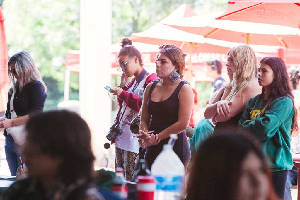 Several individuals seated standing indoors, facing a podium where a speaker is presenting during California Native American Day.