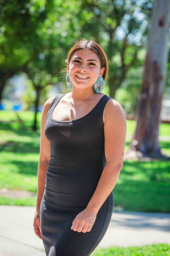 Close-up of an individual wearing beaded earrings outdoors.