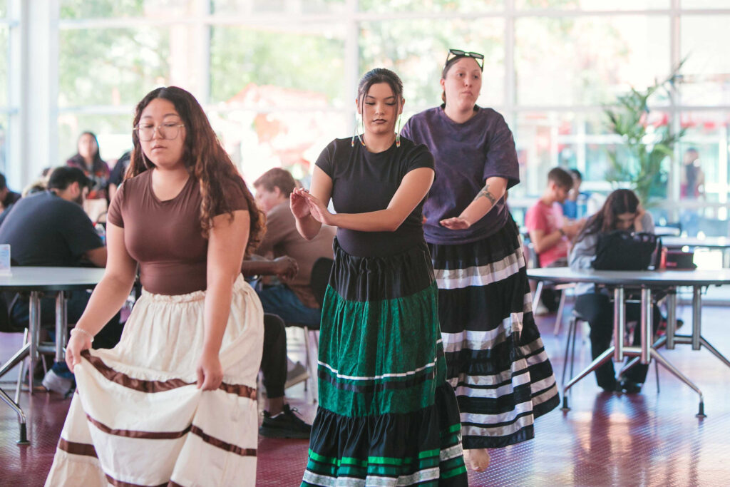 Group of individuals dancing while others observe.
