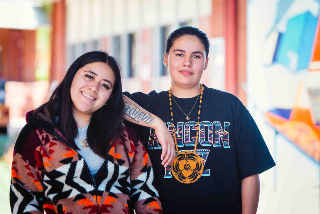Two individuals standing outdoors near greenery during California Native American Day.