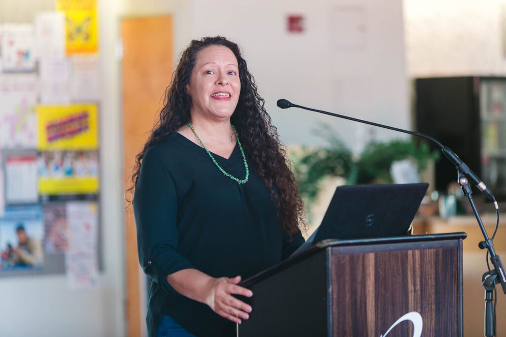 Individual speaking at a podium indoors during California Native American Day.